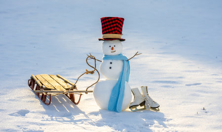 Funny holiday snowman. Snow man standing on snow. Winter blue sky with snowman. Snowman smiling in sunlight. Happy seasonal scene.の写真素材