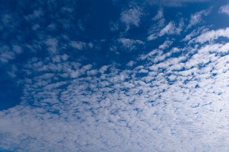 Blue sky with fluffy clouds wallpaper. Relaxation theme sky. A clear blue sky with fluffy white clouds. Clouds texture and light gradients. Serene sky view.の写真素材