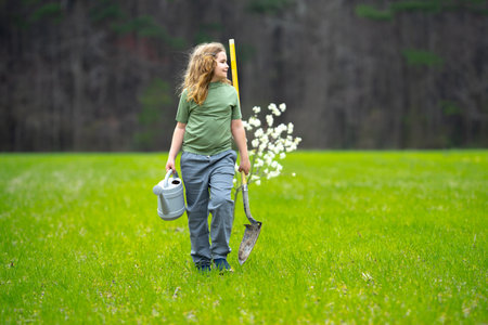 Child planting a spring tree on garden. Kids grow up fruit tree. Kid gardener with shovel. Child work in orchard with blooming trees. Children planting trees in backyard. Young farmer caring for trees.の写真素材