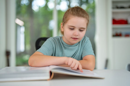 Child reading book at home. Kid studying with books in playroom. Clever boy reading story book in children room. Kid learning with book. Smart student doing homework with book in cozy interior.の写真素材