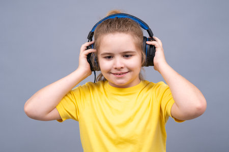Kid listens to music. Child enjoys song. Kid smiles while wearing headphones. Child feels relaxed and happy with music. Kid enjoys sound. Child relaxes in headphones studio isolated portrait.の写真素材