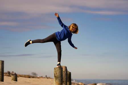 Cute boy walking on a balance beam. Children on summer vacation. Happy childhood. Kid plays near the beach. Kid enjoys sunny day. Childhood memories. Kid keeps balance outdoors.の写真素材