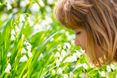 Dreamy face close-up of a spring child. Spring face portrait of blonde child. Springs child faces. Child daydreaming in spring field. Dreamy kids face in spring garden. Cute kid portrait in garden.の写真素材