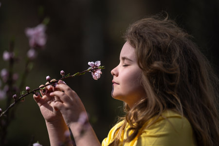 Spring child portrait. Blonde kid in a blooming meadow. Childhood joy in nature. Child with flowers on spring day. Smiling child playing outdoors in spring nature. Dreamy spring child face.の写真素材