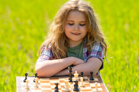 Kid plays chess. A child thinks and playing chess. Kid focuses on chessboard. The kid make checkmate.の写真素材