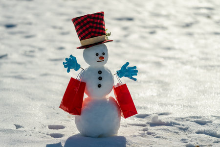 Snowman with red gift box. Christmas gift ideas for winter celebration. Snowman with winter discount. Snowman celebrating winter holidays. Snowman with festive greeting.の写真素材