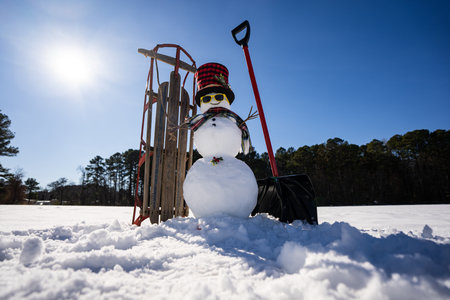 Winter background with snowman for New Year greeting card. Winter landscape with snowman, sled and snow shovel. Cozy winter design with snowman in snow.の写真素材