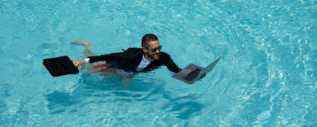 Eastern businessman taking a break. Tropical career escape. Stylish millennial enjoying success. Online work in pool. Wealthy tourist relaxing. Hot summer holiday retreat. Motivated freelancer.の写真素材