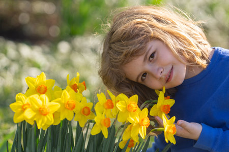 Spring fun for kids. Child play outdoors in a beautiful spring garden. Kid face in flowers. Adorable little kid in blooming cherry garden on beautiful spring day. Happy child during spring blossom.の写真素材