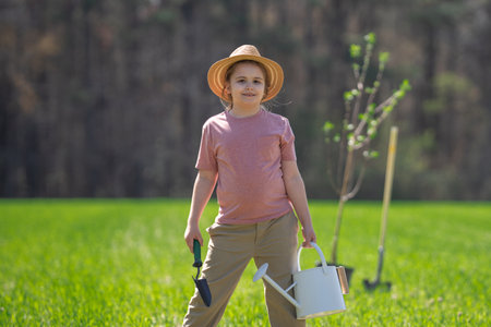 Kid gardening. Child cultivating a tree in garden. Child planting tree. Little gardener working with shovel. Spring gardening with kids. Child watering plants in garden. Child taking care of garden.の写真素材