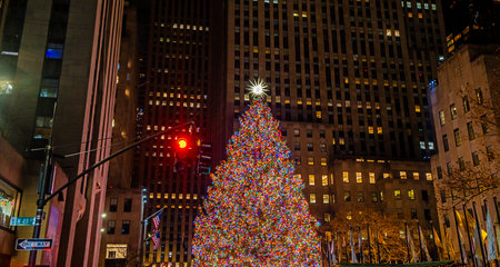 Christmas tree in NYC glowing at night. Winter holiday in New York with festive lights. New York winter cityscape with holiday decorations. New York City Christmas celebration downtown.の写真素材