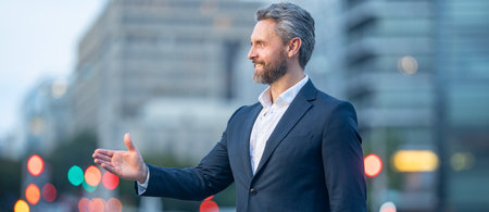 Successful middle aged businessman standing outside in an urban city street. Man in suit outdoor...