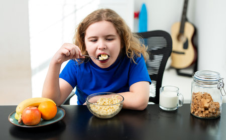 Child eating food at table. Happy kid portrait eating. Balanced breakfast nutrition. Child eating everyday meal. Healthy morning breakfast. Smiling child enjoying food.の写真素材