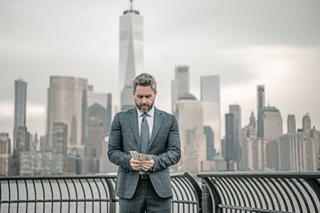 Business man with dollar outdoor. Business man excited with dollar money on street. Rich business man in suit hold dollar cash. Businessman in suit hold 100 dollars banknotes at city. Dollars banknote.の写真素材