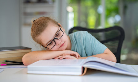 Child relaxing while reading a book at home. Teenager read book in a home interior. Little reader enjoying a story books at home. Kid reading book and learning in the playroom. Child holding a book.の写真素材