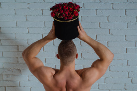 Flowers romance idea. Flowers masculine gift concept. Flowers love symbol. Man hold roses bouquet. Romantic, valentine, dating concept. Muscular man with roses gift.の写真素材