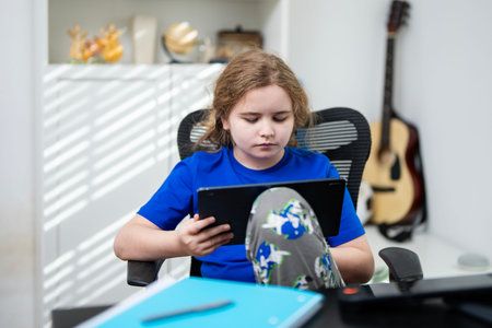 Child using laptop for class. Girl studying from home. Kid using laptop for homework. Student writing in laptop. Kid learning on laptop at home. Child studying remote school.の写真素材