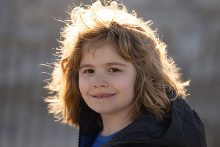 Close up portrait of a happy child looking at camera and smiling. Child in sunlight close-up outdoor...