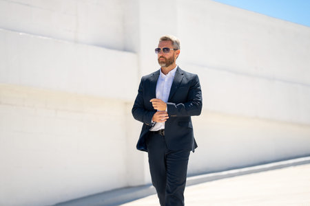 Businessman walking outdoors. Successful businessman in suit. Confident business man in suit. Business man walking away. Rich man in elegant suit. Urban business man with confidence. Success business.