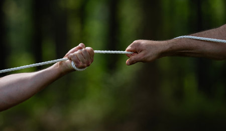 Rope conflict shows power and resistance. Human hands keep Rope under tension. Rope challenge needs endurance outdoors. Strong grip controls Rope during rivalry.