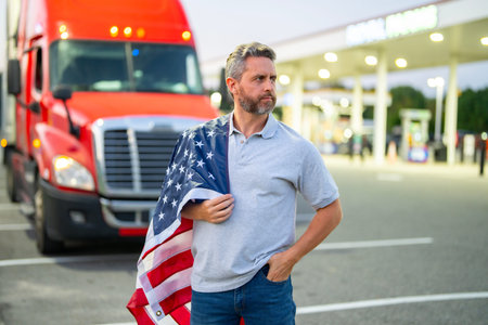 Confident man appears as truck driver. Truck driver poses beside cargo semi. Truck driver represents cargo transport. Mature trucker serves heavy trucking.