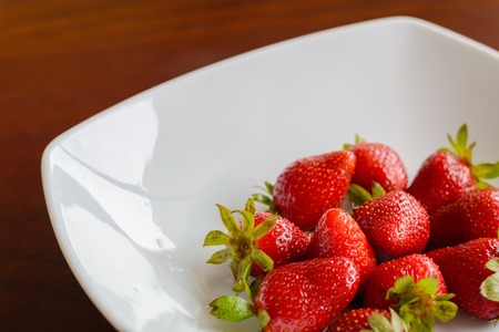 Ripe red strawberries in the plate on wooden tableの写真素材
