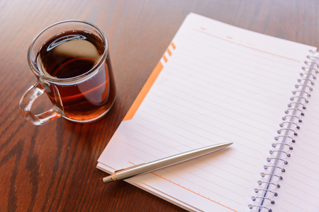 Open a blank white notebook, pen and cup of tea on the deskの写真素材
