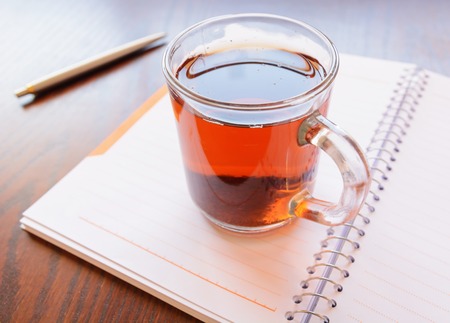 Open a blank white notebook, pen and cup of tea on the deskの写真素材