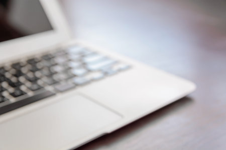 Workplace with open laptop on black modern wooden desk, soft focus