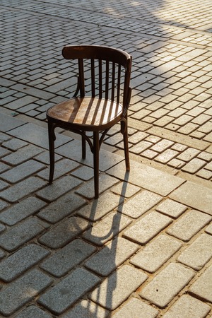 Old Viennese chair on the cobbles in the ray of setting sunの写真素材