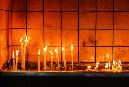 burning wax candles in the temple in front of the tiled wall in the waterの写真素材