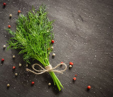 A bunch of fresh dill on dark wood background. Empty space for text.の写真素材