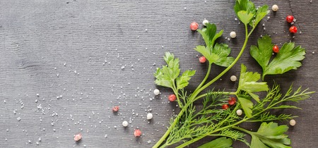Fragrant fresh parsley and dill arranged on a diagonal on a dark background. White and red pepper peas.の写真素材