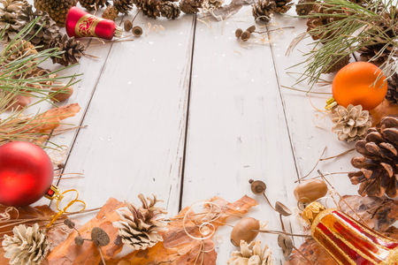 Abstract Christmas frame with cones, pine bark, acorns, and Christmas toys. White wooden background. Space for text. View angle of 45 degrees.の写真素材