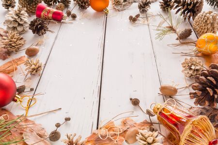 Abstract Christmas frame with cones, pine bark, acorns, and Christmas toys. White wooden background. Space for text. View angle of 45 degrees.の写真素材