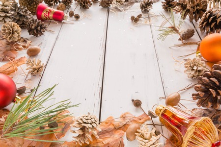Abstract Christmas frame with cones, pine bark, acorns, and Christmas toys. White wooden background. Space for text. View angle of 45 degrees.の写真素材