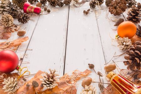 Abstract Christmas frame with cones, pine bark, acorns, and Christmas toys. White wooden background. Space for text. View angle of 45 degrees.の写真素材