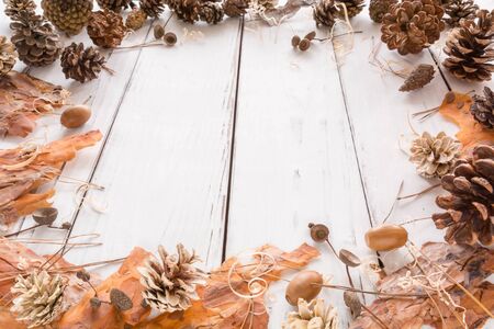 Abstract Christmas frame with cones, pine bark, acorns, and Christmas toys. White wooden background. Space for text. View angle of 45 degrees.の写真素材