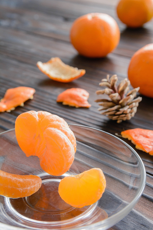 slices of orange and a ripe tangerine in a glass saucer. Against the background of the old wooden table. View angle of 45 degrees.の写真素材