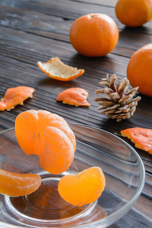 slices of orange and a ripe tangerine in a glass saucer. Against the background of the old wooden table. View angle of 45 degrees.の写真素材