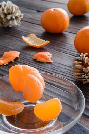 slices of orange and a ripe tangerine in a glass saucer. Against the background of the old wooden table. View angle of 45 degrees.の写真素材
