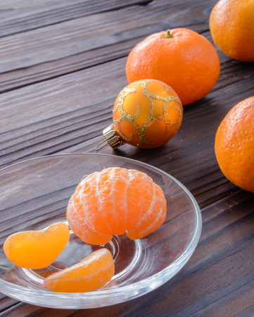 slices of orange and a ripe tangerine in a glass saucer. Against the background of the old wooden table. View angle of 45 degrees.の写真素材