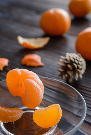 slices of orange and a ripe tangerine in a glass saucer. Against the background of the old wooden table. View angle of 45 degrees.の写真素材