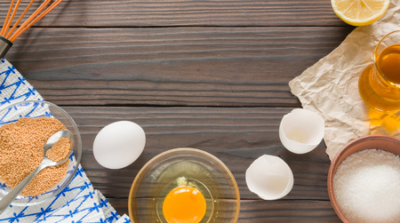 The process of making homemade mayonnaise. Eggs, oil, and other ingredients. View from above, against the dark wooden table.の写真素材