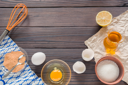 The process of making homemade mayonnaise. Eggs, oil, and other ingredients. View from above, against the dark wooden table.の写真素材