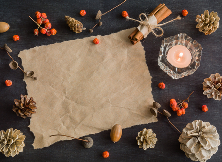 Dark Christmas background with candles and berries of mountain ash. White pine cones and branches with acorns. Cinnamon tied with string. Top view.の写真素材