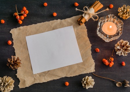 Dark Christmas background with candles and berries of mountain ash. White pine cones and branches with acorns. Cinnamon tied with string. Top view.の写真素材