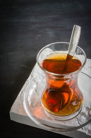 Transparent cup of thin glass and black tea. Spoon into a glass. Empty placeの写真素材