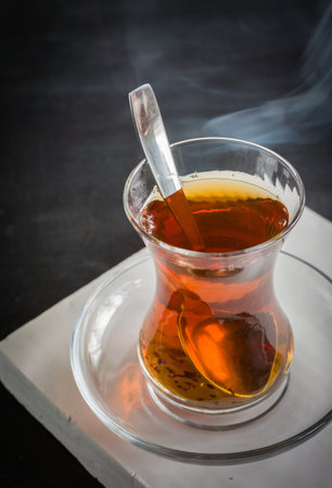 Transparent cup of thin glass and black tea. Spoon into a glass. Empty place