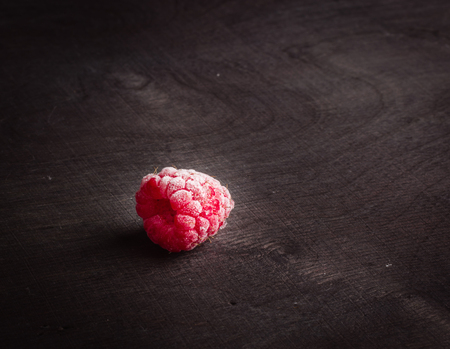 Frozen raspberrieson dark wood. Frost on the berries. Red and black.の写真素材